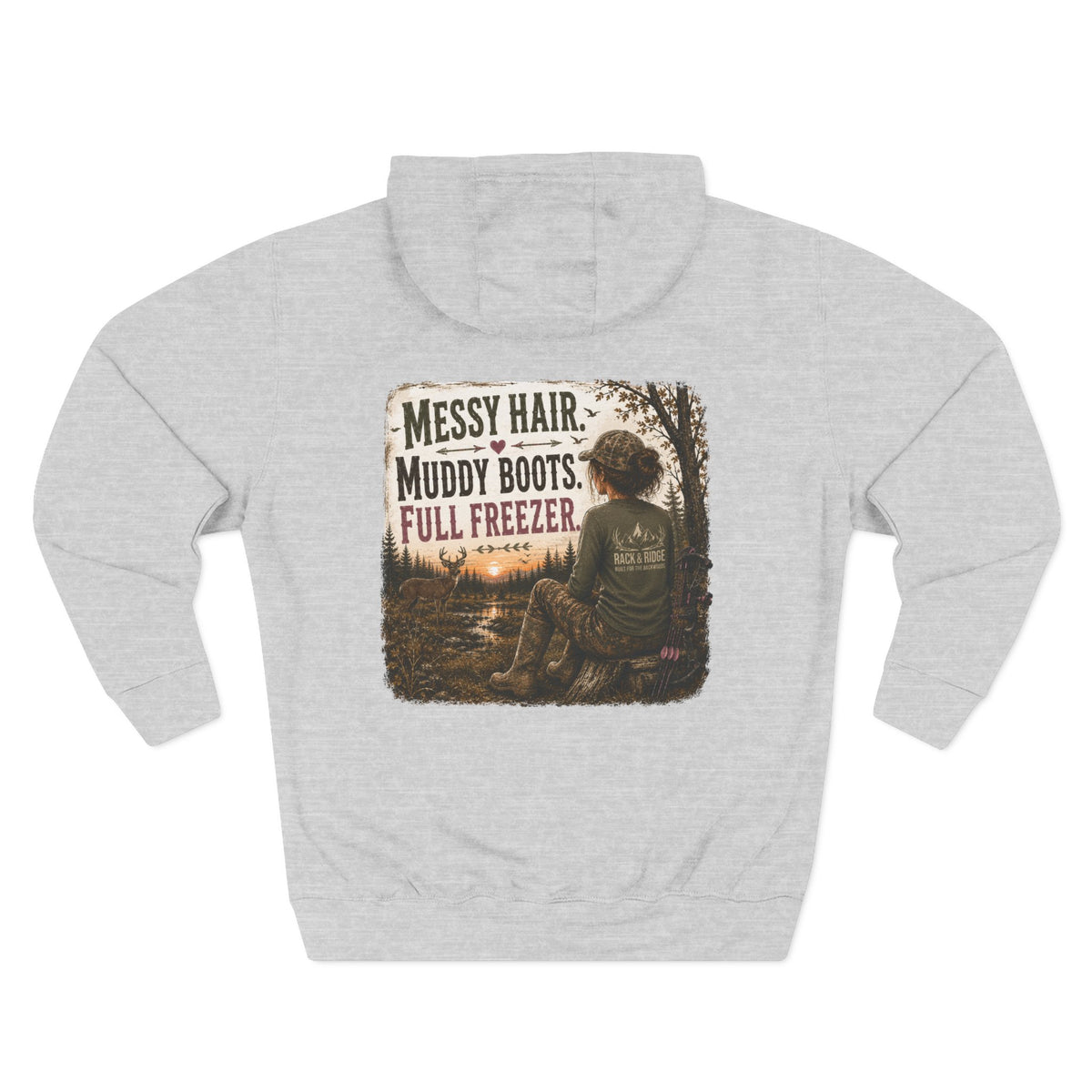 A light heather gray pullover hoodie shown from the back, featuring a large square graphic print with the text 'MESSY HAIR, MUDDY BOOTS, FULL FREEZER.' and an illustration of a person sitting in a wooded outdoor scene.